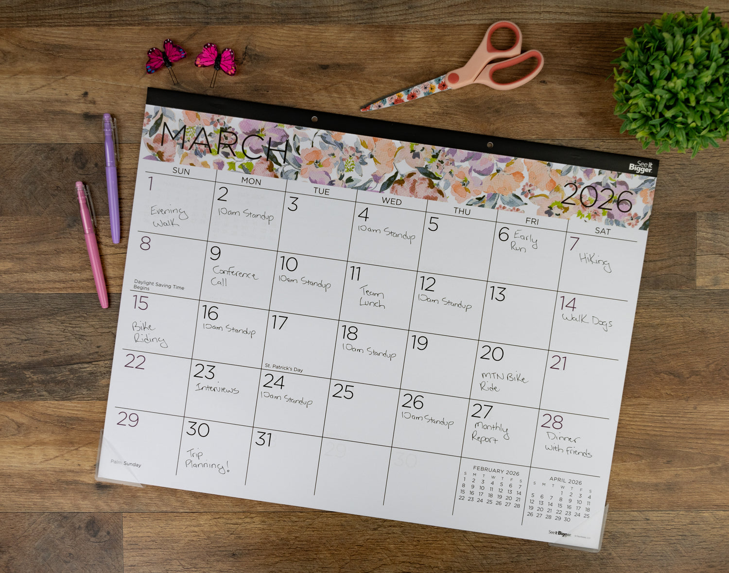 Floral March 2026 calendar on a wooden surface with stationery items.