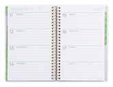 Opened 2026-2027 planner with floral cover displaying monthly/weekly layout. Medium 2026 planner.