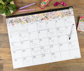 Floral-themed calendar for April 2026 on a wooden surface with stationery items.